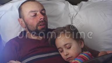 父亲给女儿读<strong>睡前</strong>故事。 女儿<strong>睡</strong>在她父亲身边，父亲读她的书。