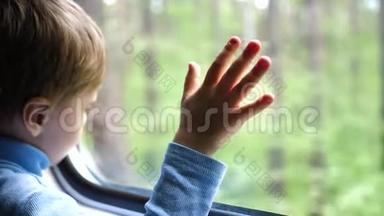 这个男孩坐火车旅行，望着窗外，看着窗外移动的物体。 手工特写