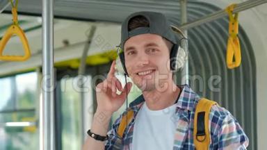 年轻的帅哥在<strong>公共交通工具</strong>中享受旅行，站在现代电车上戴着耳机