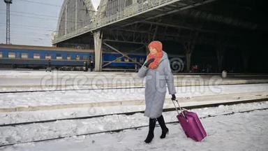 户外视频：穿着蓝色<strong>外套</strong>的年轻女子在冬天带着<strong>紫色</strong>的行李箱在火车站赶来