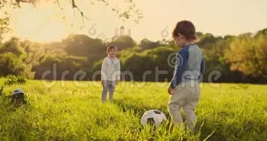 两个可爱的小孩子，一起踢足球，夏天。 孩子们在户外踢足球。