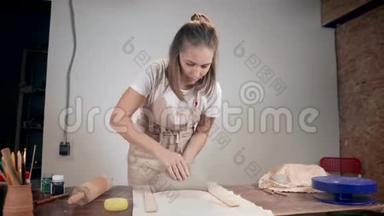 女人在陶艺工作室用擀面杖在桌子上展开粘土