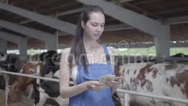 奶牛场上年轻漂亮的女<strong>职工</strong>微笑着数钱的画像。 积极的农民从农场得到收入