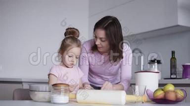 可爱的小女孩和她漂亮的妈妈在厨房里揉面团的时候玩得很<strong>开心</strong>，笑得很<strong>开心</strong>。 女孩触摸