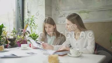 两个女商人在咖啡馆里讨论工作问题并翻阅文件