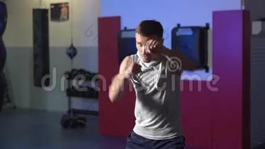 拳击手训练在健身房向摄像机投掷拳头，影子在缓慢运动中战斗。