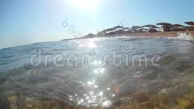 一台摄像机拍摄的视频，它在海岸附近的海浪上拍打着，上面有一把茅草伞和一把躺椅，一个超宽的圆形