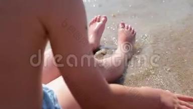 一个男孩坐在海边，捕捉<strong>海浪</strong>。 <strong>海浪</strong>冲刷着男孩`脚.. 有孩子的家庭的海上假期。