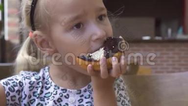 有趣的小女孩在咖啡馆的桌子上吃甜<strong>巧克力甜甜圈</strong>。 可爱的金发女孩咬着<strong>巧克力甜甜圈</strong>