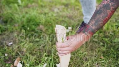 一个手臂上有纹身的人正试图用斧头砍木头。