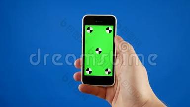 快关门。 一个男人`手拿着一个绿色屏幕的智能手机，做滑动、触摸和滚动手势。 蓝色