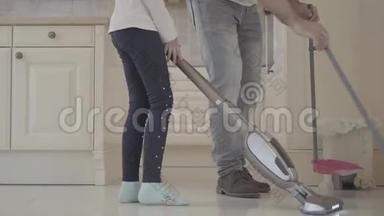 爸爸和女儿在干净的房子里玩得很开心。 一个拿着扫帚和<strong>簸箕</strong>的男人和一个拿着吸尘器的女孩。 消遣时间