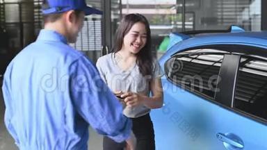 汽车修理工在汽车修理厂买车或维修后，把车钥匙交给女顾客驾驶。