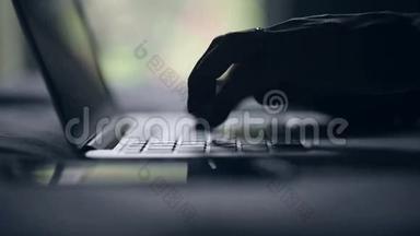 手的剪影在键盘MacBook上。 手指键入文本。