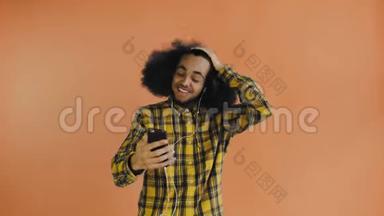年轻的非裔美国人视频电话与电话橙色背景。 情感概念