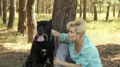 在一个<strong>夏日</strong>的阳光明媚的日子里，针叶林中的一个美丽的女人正和她心爱的狗卡尼·科索·布莱克在<strong>树下</strong>休息