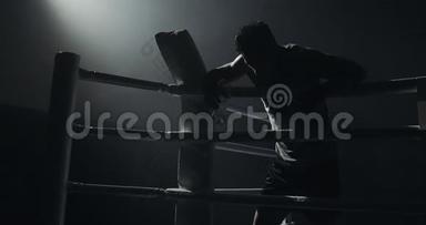 疲惫的男拳击手拿着一瓶水休息在戒指的<strong>话题</strong>上。 剪影。 拳击概念。