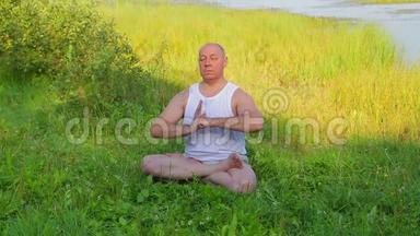 一个中年人早上在湖边做呼吸瑜伽和冥想。