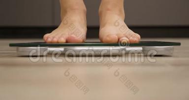 人类赤脚在厨房测量体重或超重。 体重秤上的女人。 减肥概念