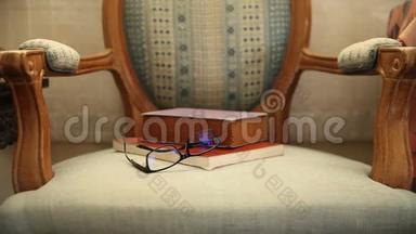 自然光<strong>线下</strong>旧椅子上的眼镜和书籍