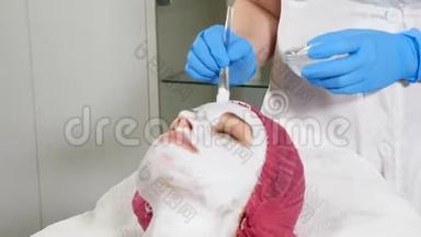 美容师将白色抗衰<strong>老面</strong>膜敷在脸上。 美的概念。 三十多岁的年轻女子在水疗中心
