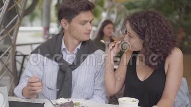 一对幸福夫妇坐在户外咖啡馆吃蛋糕的肖像。 <strong>年轻</strong>人和女人一起享受他们的晚餐。 这<strong>就是</strong>