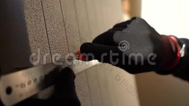 关闭手工人在黑色和红色手套使用金属标尺切割片的隔热灰色。