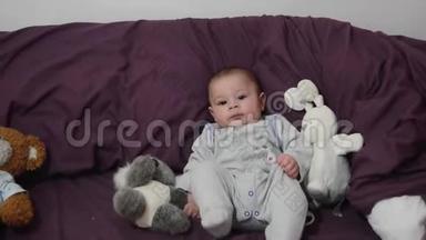 可爱的4个月大的男孩穿着紫色的床上用品和兔子玩具