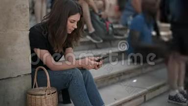 巴黎卢浮宫附近的楼梯上坐着智能手机的女人发短信。