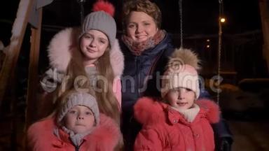 白种人的母亲和三个女儿在晚上的城市里吃着雪，高兴地看着镜头的家庭画像