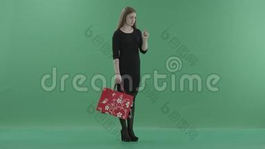美丽的女人穿着黑色的小连衣裙，手里拿着购物袋，在数字<strong>屏幕</strong>上<strong>滚动</strong>。 她站在右边