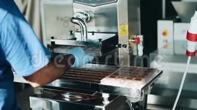 糖果者用一台特殊的机器把<strong>巧克力</strong>倒入模具中。 后景。