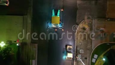 在城市街道的道路上铺设沥青的人员和设备，从无人驾驶飞机俯瞰夜景