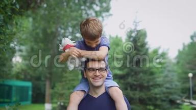 穿着蓝色衬衫的帅哥和他的儿子在街上散步。 男<strong>家长</strong>向儿童展示城市景观。 坐着的男孩