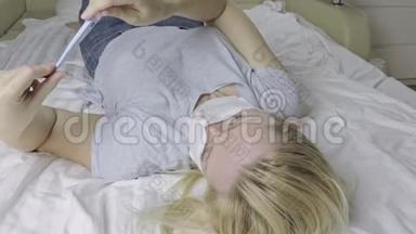 带着医用口罩躺在床上测<strong>量体温</strong>的患病妇女