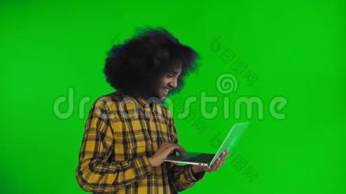 快乐的非裔美国人使用笔记本电脑，微笑着离开绿色屏幕或色度键背景。 概念