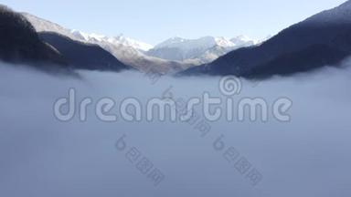 在山间山谷中，无人机飞过薄雾。 雪峰般的雾山