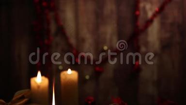 圣诞节的气氛：三支点燃的蜡烛，一支在前景上有大火焰的蜡烛，红色和金色的，脱钩的球，缎子的金丝带，