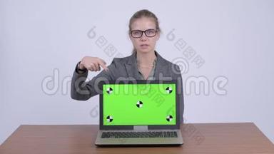 年轻快乐的金发女<strong>商人展示</strong>笔记本电脑，并在办公桌上<strong>展示</strong>一些东西