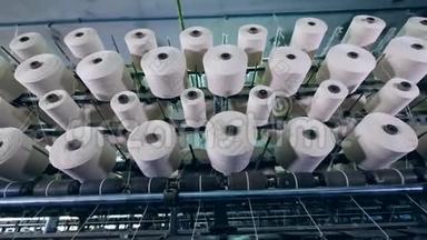 纺织厂设备上用白色纤维旋转筒管.. 纺织厂设备在工作..