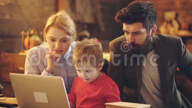 幸福的家庭一起看电影。 带笔记本电脑的小孩妈妈和爸爸用笔记本电脑看动画片