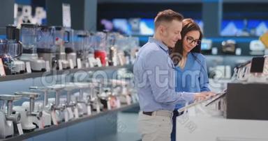 年轻漂亮的已婚夫妇一个穿着衬衫的男人和一个戴着智能手机的女人站在展示台旁