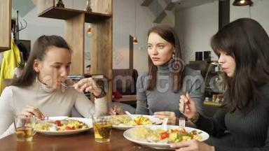 三个女朋友在咖啡馆里<strong>一起吃饭</strong>，聊天，享受他们的食物。
