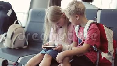 一个男孩和一个女孩坐在机场<strong>玩手机</strong>。