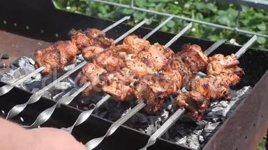 一个人`双手转动扦子。 什什烤肉串。 烧肉，鸡肉或羊肉肉片被烧在木炭烤架上。 烤烤