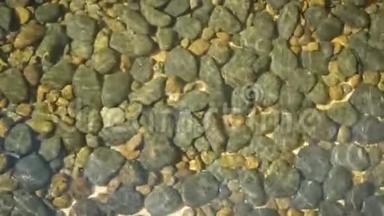 干净的圆形石头在水晶水中清晰可见。 上面是干净的水晶水和灰色的黄色卵石