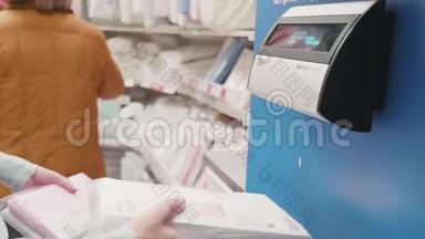 女士使用价格检查机。 妇女自助检查超市产品价格