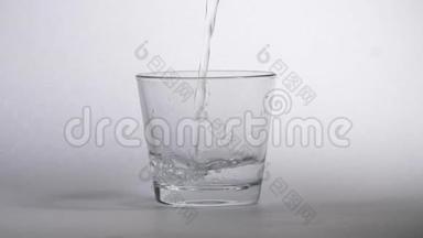 将新鲜纯净水倒入桌上的透明玻璃杯中，健康和饮食理念