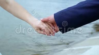 穿着节日经典服装的男人和女人在流动的水背景下携手合作。 双手特写