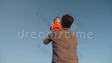 父亲把女儿扔到蓝天上。 爸爸和一个小孩子在他的<strong>怀里</strong>对抗天空。 幸福的家庭在玩耍